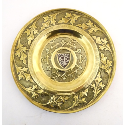 818 - An Arts & Crafts brass charger with hammered detail, central shield with inlaid EF monogram with the... 