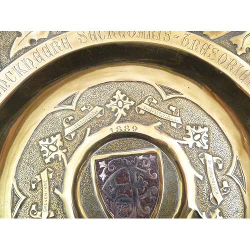 818 - An Arts & Crafts brass charger with hammered detail, central shield with inlaid EF monogram with the... 