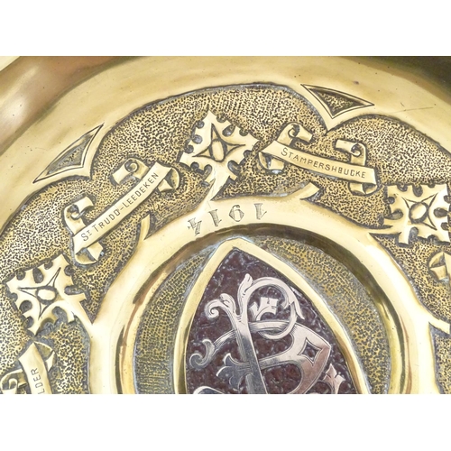 818 - An Arts & Crafts brass charger with hammered detail, central shield with inlaid EF monogram with the... 