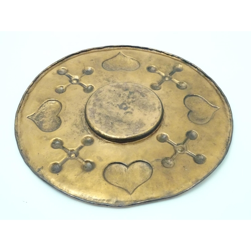 810 - An Arts & Crafts hammered copper charger with embossed detail depicting hearts and crosses. Approx. ... 