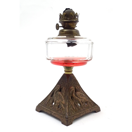 1521 - An Arts and Crafts oil lamp with cast bird decoration to the base and having facet cut clear glass r... 