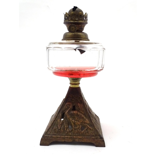 1521 - An Arts and Crafts oil lamp with cast bird decoration to the base and having facet cut clear glass r... 