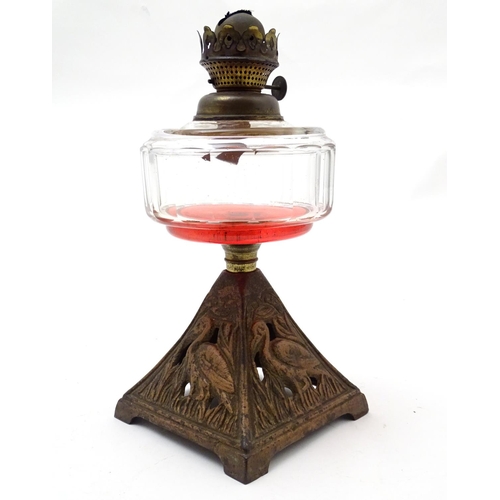 1521 - An Arts and Crafts oil lamp with cast bird decoration to the base and having facet cut clear glass r... 