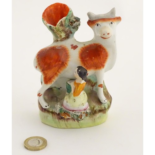 76 - A 19thC flatback Staffordshire Pottery spill vase formed as a milk maid milking a cow. Approx. 4 3/4... 