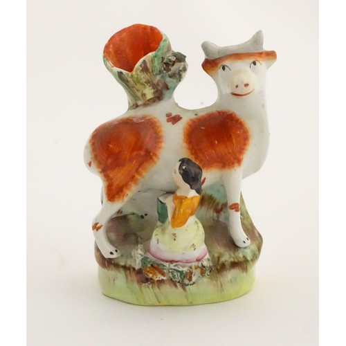 76 - A 19thC flatback Staffordshire Pottery spill vase formed as a milk maid milking a cow. Approx. 4 3/4... 