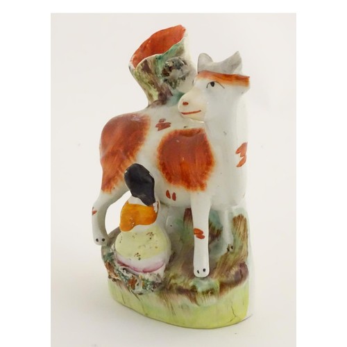 76 - A 19thC flatback Staffordshire Pottery spill vase formed as a milk maid milking a cow. Approx. 4 3/4... 