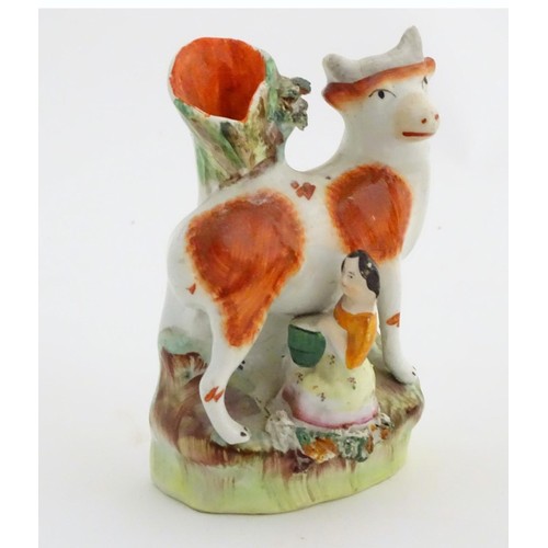 76 - A 19thC flatback Staffordshire Pottery spill vase formed as a milk maid milking a cow. Approx. 4 3/4... 