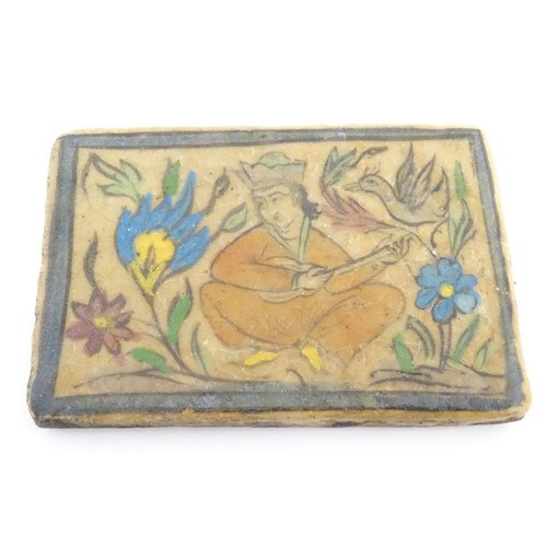 93 - A 19thC rectangular Persian tile with hand painted decoration depicting a seated man playing a music... 