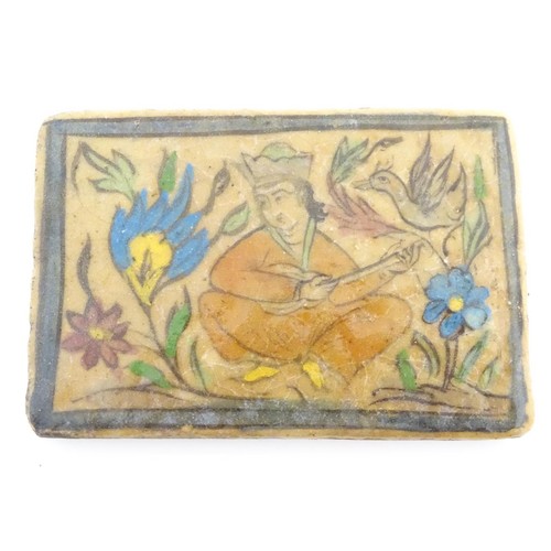 93 - A 19thC rectangular Persian tile with hand painted decoration depicting a seated man playing a music... 