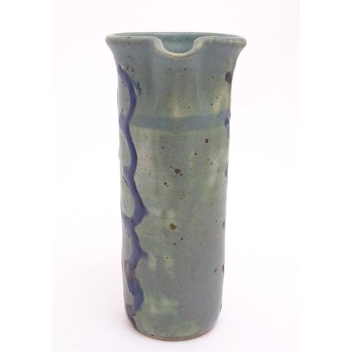 99 - A studio pottery jug of cylindrical form with a green ground and blue detail. Impressed maker's mark... 