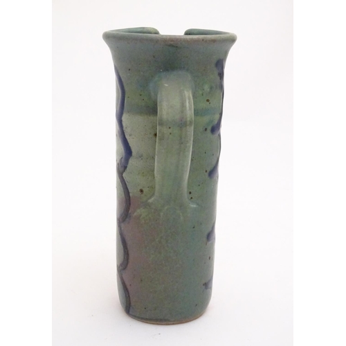 99 - A studio pottery jug of cylindrical form with a green ground and blue detail. Impressed maker's mark... 