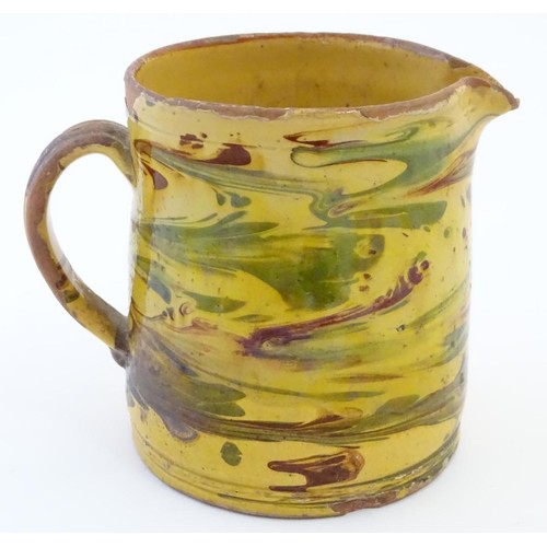 104 - A 19thC studio pottery slipware jug with a yellow ground. Indistinct incised mark under. Approx. 5''... 