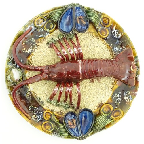 172 - A 20thC Portuguese Palissy style majolica dish with an applied model of a lobster on a bed of sand a... 