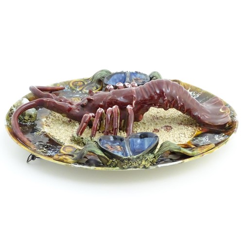 172 - A 20thC Portuguese Palissy style majolica dish with an applied model of a lobster on a bed of sand a... 