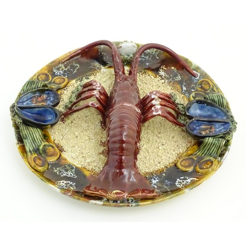 172 - A 20thC Portuguese Palissy style majolica dish with an applied model of a lobster on a bed of sand a... 