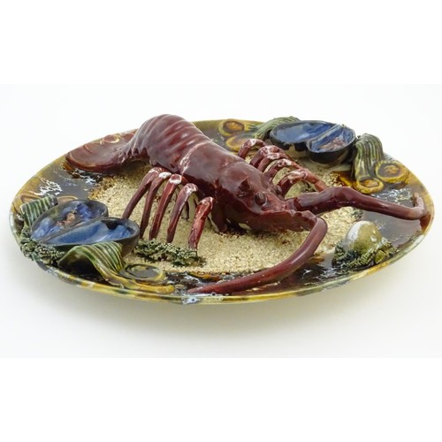 172 - A 20thC Portuguese Palissy style majolica dish with an applied model of a lobster on a bed of sand a... 