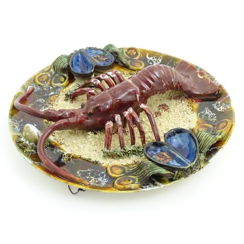 172 - A 20thC Portuguese Palissy style majolica dish with an applied model of a lobster on a bed of sand a... 