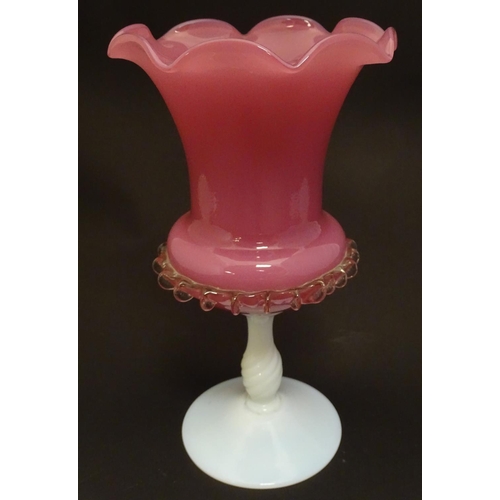 199 - A glass vase, the pink glass body with wavy rim and clear frilled decoration, raised over a milk gla... 