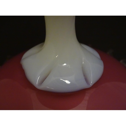 199 - A glass vase, the pink glass body with wavy rim and clear frilled decoration, raised over a milk gla... 