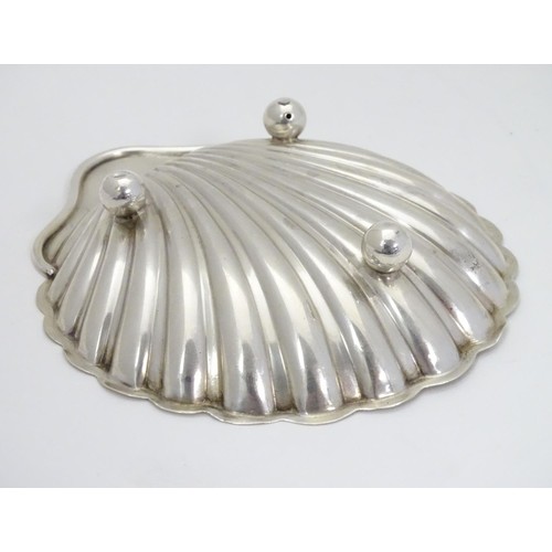 236 - A silver scallop-shaped dish raised on three bun feet. Hallmarked Sheffield 1910 maker Harrison Brot... 