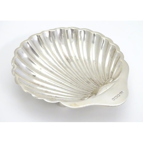 236 - A silver scallop-shaped dish raised on three bun feet. Hallmarked Sheffield 1910 maker Harrison Brot... 