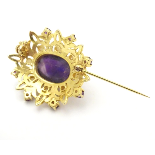 580 - A 9ct gold brooch set with central oval cabochon amethyst surrounded by eight seed
pearls, further s... 