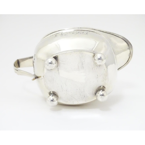 240 - A George III silver cream / milk jug with banded decoration raised on four spherical feet. Hallmarke... 