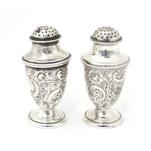 248 - A pair of silver pepper pots with embossed formal and C-scroll decoration, hallmarked Sheffield 1897... 