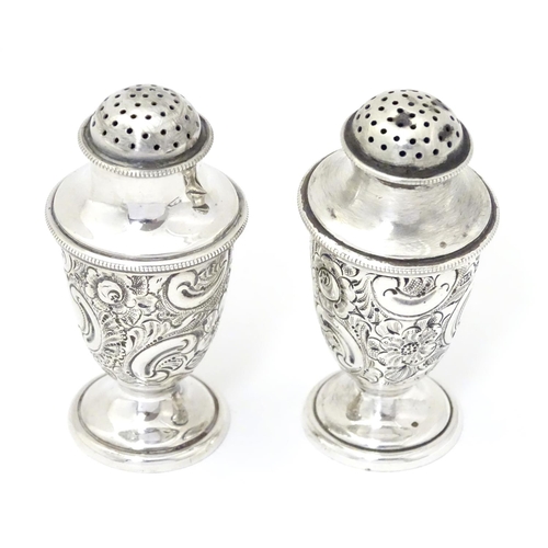 248 - A pair of silver pepper pots with embossed formal and C-scroll decoration, hallmarked Sheffield 1897... 