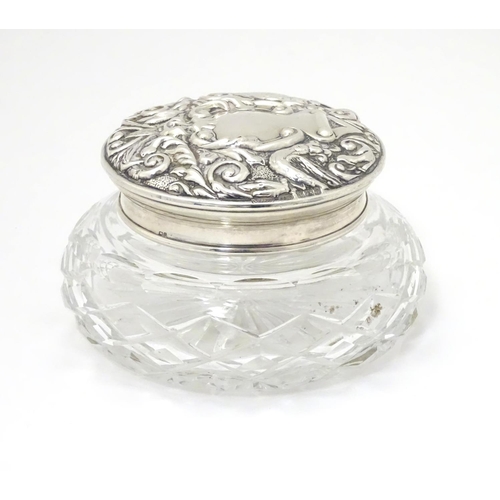 249 - A cut glass powder jar with embossed silver lid, hallmarked Birmingham 1976 maker W I Broadway & Co ... 