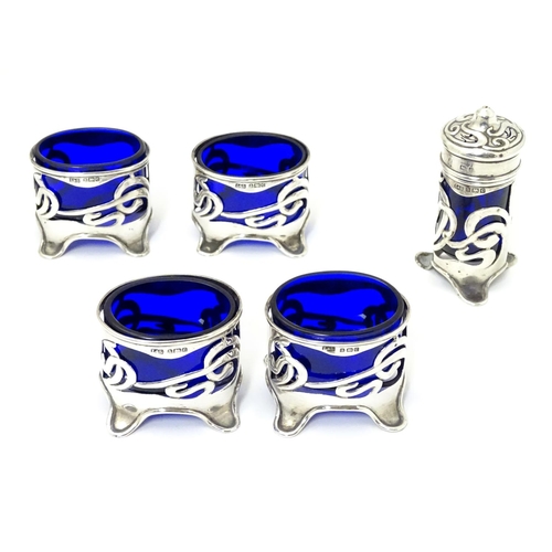 272 - An Art Nouveau silver cruet set comprising four salts and a pepper with blue glass liners and scroll... 