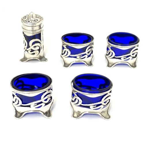 272 - An Art Nouveau silver cruet set comprising four salts and a pepper with blue glass liners and scroll... 