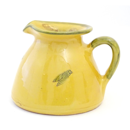 128 - A terracotta jug with a yellow glaze and incised crickets / insects. Approx. 5 1/2