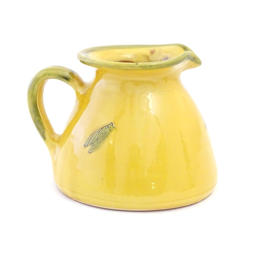 128 - A terracotta jug with a yellow glaze and incised crickets / insects. Approx. 5 1/2