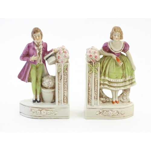 136 - A pair of German porcelain figural bookends depicting a gentleman and a lady with flowers. Marked 18... 