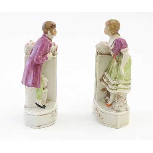 136 - A pair of German porcelain figural bookends depicting a gentleman and a lady with flowers. Marked 18... 