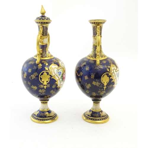 140 - Two Royal Doulton pedestal vases with cobalt blue ground, gilt highlights and hand painted floral an... 