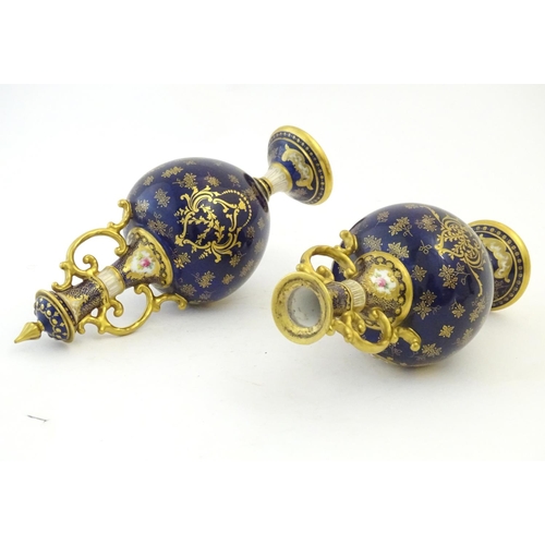 140 - Two Royal Doulton pedestal vases with cobalt blue ground, gilt highlights and hand painted floral an... 