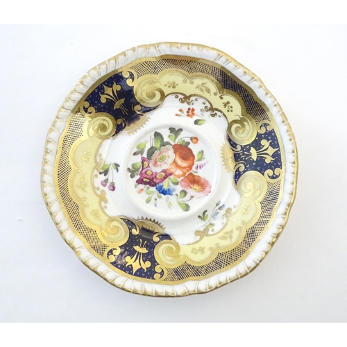 141 - A hand painted tea cup and saucer with a blue ground, gilt highlights and central flower decoration.... 