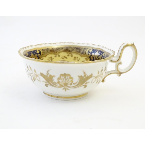 141 - A hand painted tea cup and saucer with a blue ground, gilt highlights and central flower decoration.... 