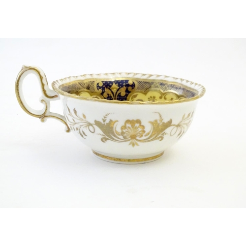 141 - A hand painted tea cup and saucer with a blue ground, gilt highlights and central flower decoration.... 