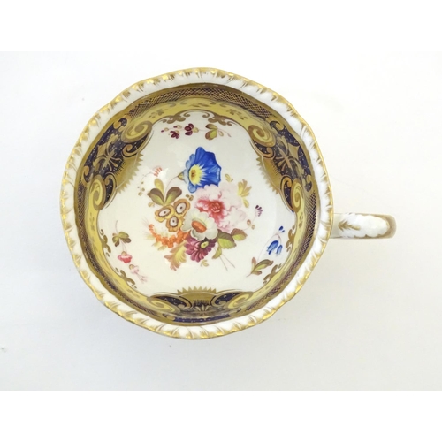 141 - A hand painted tea cup and saucer with a blue ground, gilt highlights and central flower decoration.... 