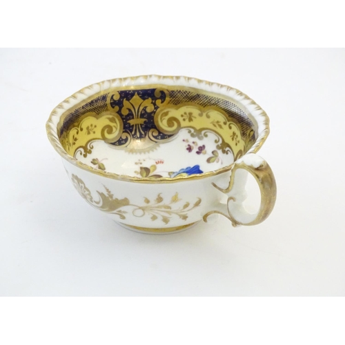 141 - A hand painted tea cup and saucer with a blue ground, gilt highlights and central flower decoration.... 