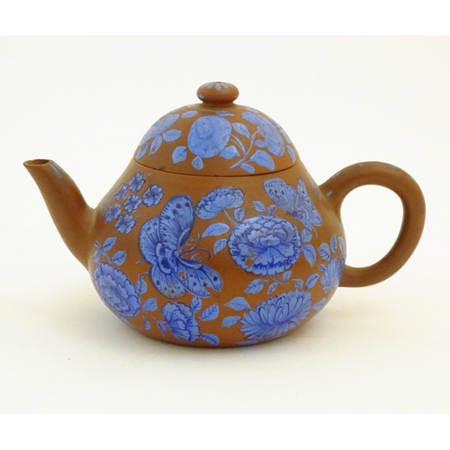 57 - A Chinese Yixing clay teapot with blue flower and butterfly decoration. Incised character marks unde... 