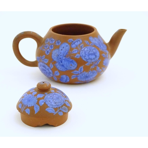 57 - A Chinese Yixing clay teapot with blue flower and butterfly decoration. Incised character marks unde... 