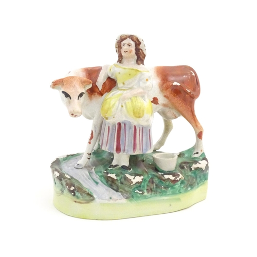 77 - A Staffordshire model of a cow with a milkmaid on a naturalistic base. Approx. 6 1/2