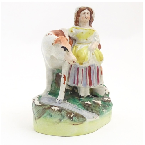 77 - A Staffordshire model of a cow with a milkmaid on a naturalistic base. Approx. 6 1/2