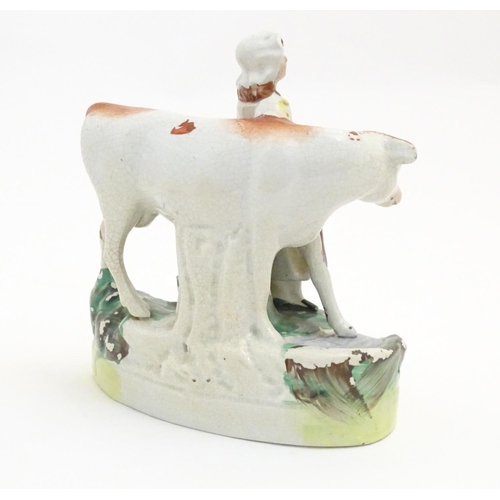 77 - A Staffordshire model of a cow with a milkmaid on a naturalistic base. Approx. 6 1/2