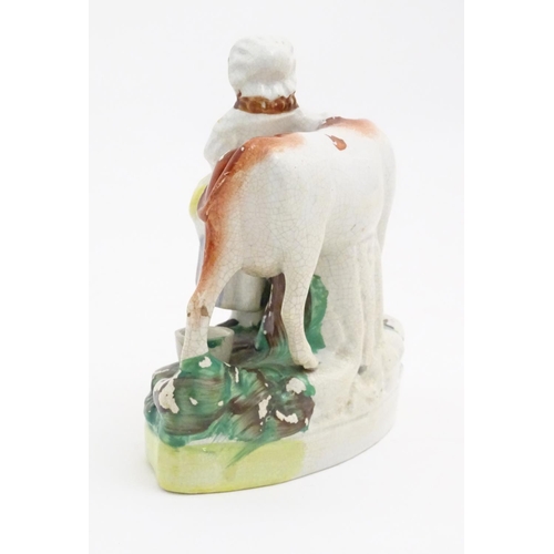 77 - A Staffordshire model of a cow with a milkmaid on a naturalistic base. Approx. 6 1/2