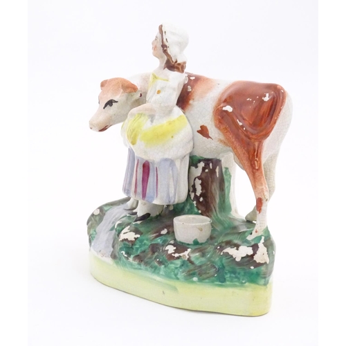 77 - A Staffordshire model of a cow with a milkmaid on a naturalistic base. Approx. 6 1/2